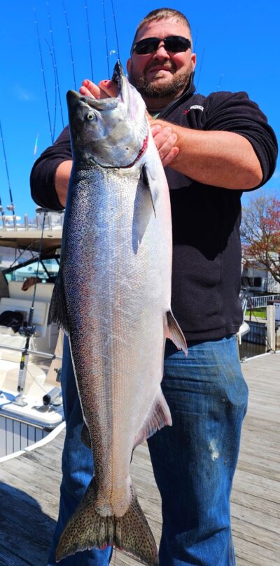 a man holding a big fish on lake ontario.
