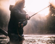 a man holding a fishing rod in a river