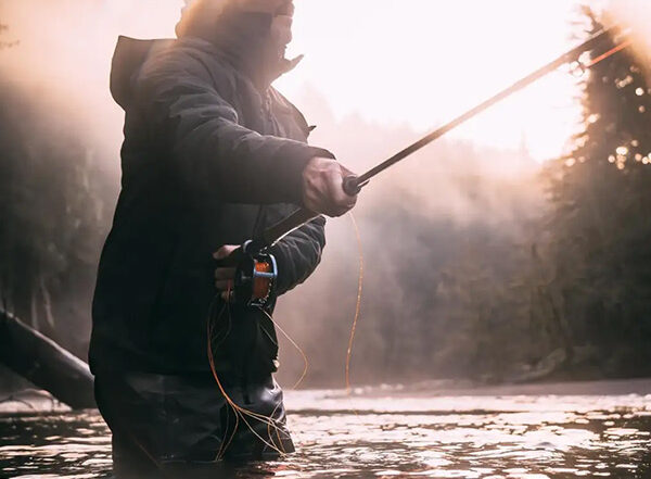 a man holding a fishing rod in a river